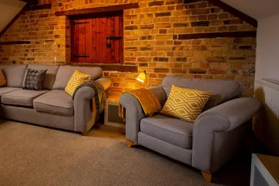 a living room with two couches and a brick wall at Y Beudy
