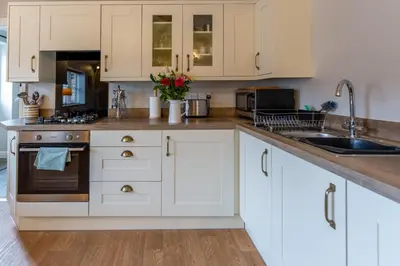 a kitchen with white cabinets and a sink at Penrhyllan