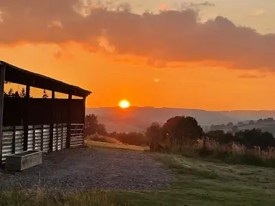 a barn with the sunset in the background at Penrhyllan