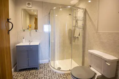a bathroom with a shower and a toilet and a sink at Penrhyllan