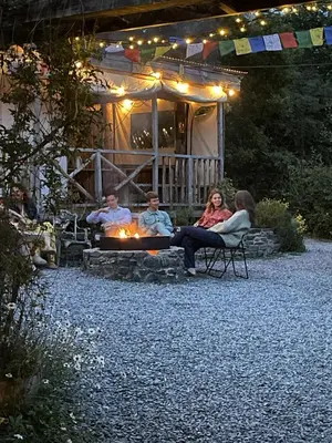 a group of people sitting around a fire in front of a house at Naturesbase Lodge in Cilcennin