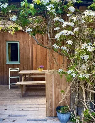 a wooden table and a bench in front of a fence at Naturesbase Lodge in Cilcennin