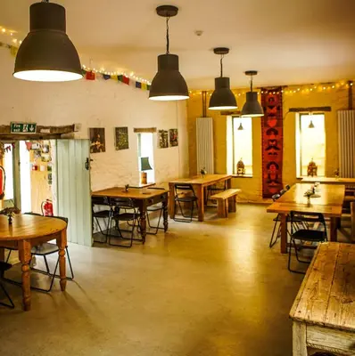 a restaurant with wooden tables and chairs and lights at Naturesbase Lodge in Cilcennin