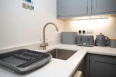 a kitchen sink with a black keyboard on the counter at Dolphin View New Quay in New Quay