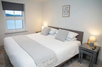 a bedroom with a large white bed with a window at Dolphin View New Quay in New Quay