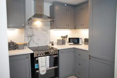 a kitchen with white cabinets and a stove top oven at Dolphin View New Quay in New Quay