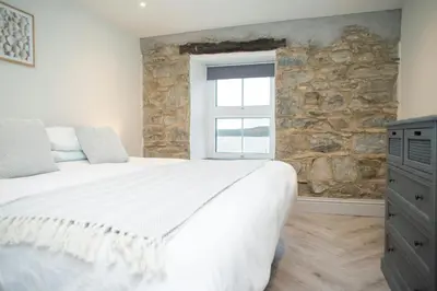 a bedroom with a large bed and a stone wall at Bay View New Quay in New Quay