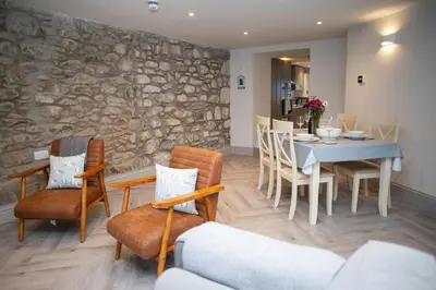 a dining room with a stone wall and a table and chairs at Bay View New Quay in New Quay