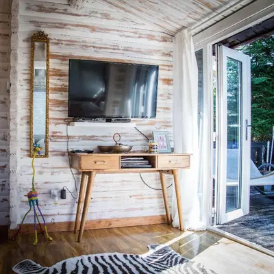 a room with a wooden table with a television on a wall at Wunder Lodge - Snowdonia Log Cabin in Trawsfynydd