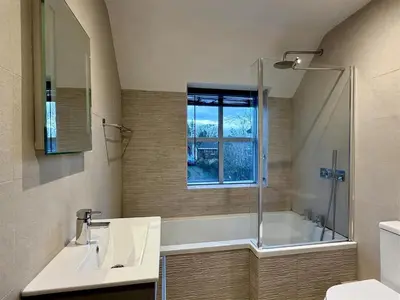 a bathroom with a tub and a sink and a shower at Woodland View House in Norton Canon