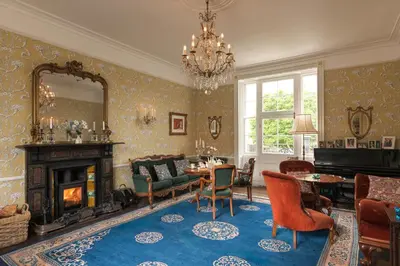 a living room with a fireplace and a table and chairs at Belmont House in Hay-on-Wye