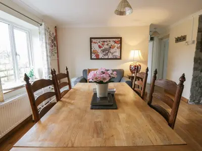 a dining room with a wooden table with flowers on it at Glanyrafon Smithy in Llandysul