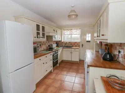 a kitchen with white cabinets and a white refrigerator at Glanyrafon Smithy in Llandysul