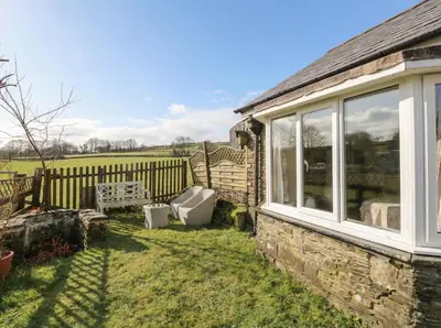 a house with a window and a chair in the yard at Glanyrafon Smithy in Llandysul