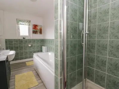 a bathroom with a shower and a tub and a sink at Glanyrafon Smithy in Llandysul