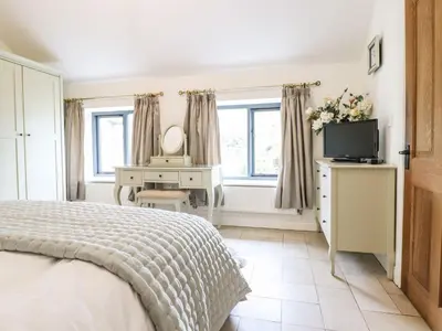 a bedroom with a bed and a desk and a television at The Talkhouse Cottage in Caersws