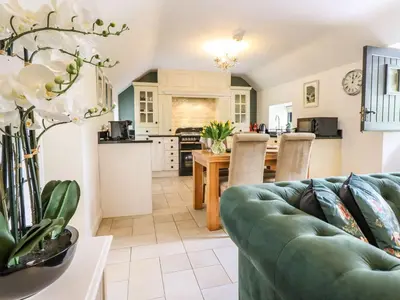 a living room with a couch and a kitchen at The Talkhouse Cottage in Caersws