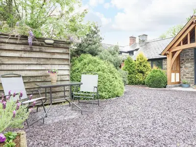 a patio with a table and chairs in a yard at The Talkhouse Cottage in Caersws