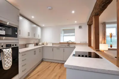 a kitchen with white cabinets and a stove top oven at Finest Retreats - Brecon House in Builth Wells