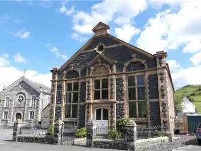 a large building with a fence in front of it at Capel Pennal in Pennal