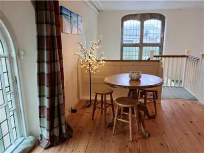 a dining room with a table and stools in a room at Capel Pennal in Pennal