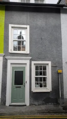 a gray house with a green door and two windows at Neifion in Aberdyfi