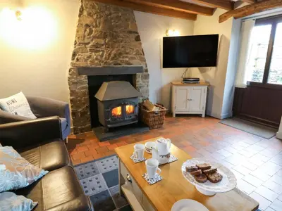a living room with a fireplace and a table with food at Old Farmhouse Cottage in New Quay