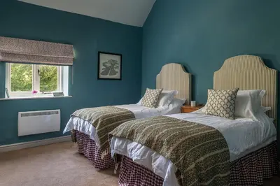 two beds in a room with blue walls at Wyvern House in Alberbury