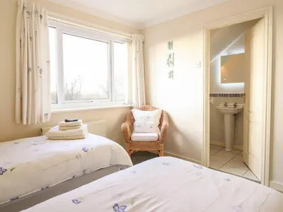 two beds in a room with a window and a chair at Llwyn Derw in Talybont