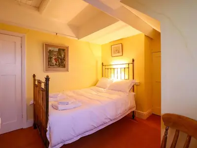 a bedroom with a large bed with white sheets at Murmur Y Don in Harlech