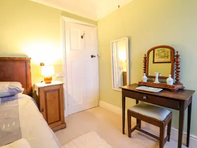 a bedroom with a desk with a mirror and a bed at Murmur Y Don in Harlech