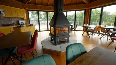 a fireplace in a room with chairs and tables at Nantsidyll Farm Spa & Holiday Lodges in Mydroilin