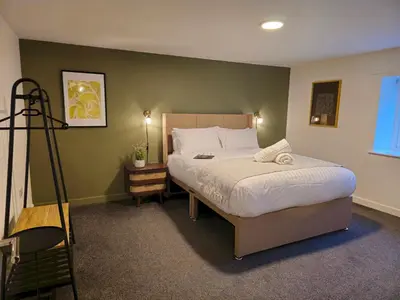 a bedroom with a large bed with white sheets at Stylish and spacious lower ground floor apartment -Pass the Keys in Shrewsbury