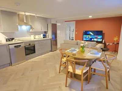 a kitchen and a living room with a table and chairs at Stylish and spacious lower ground floor apartment -Pass the Keys in Shrewsbury