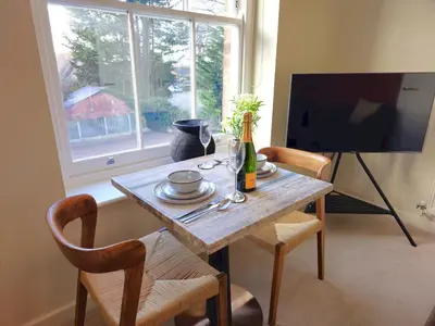 a dining room table with a bottle of wine and a window at Contemporary first-floor apartment close to town - Pass the Keys in Shrewsbury