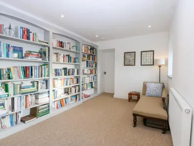 a library with white shelves filled with books at Yr Hen Felin in Dyffryn