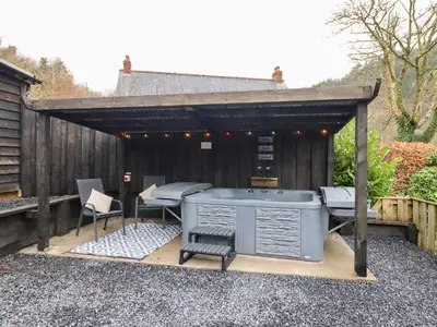 a patio with a hot tub and a grill at Lodge at Nadur in Machynlleth