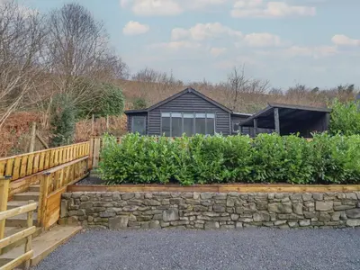 a house with a stone wall and a fence at Lodge at Nadur in Machynlleth