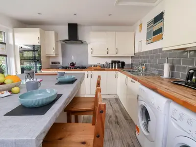 a kitchen with white cabinets and a washer and dryer at Castellolwg in Llangollen