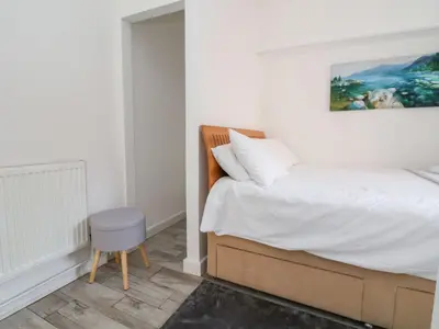 a bedroom with a bed with a chair and a painting at Castellolwg in Llangollen