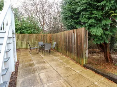 a patio with a table and chairs next to a fence at Beechwood Lodge in Borth