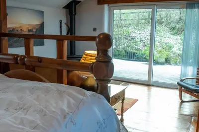 a bedroom with a bed and a large sliding glass door at The Granary - Wild Swimming, Sauna, Peace & Quiet, Nr Bala in Corwen