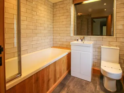 a bathroom with a tub and a toilet and a sink at 1 Clarkes Lane in Oswestry