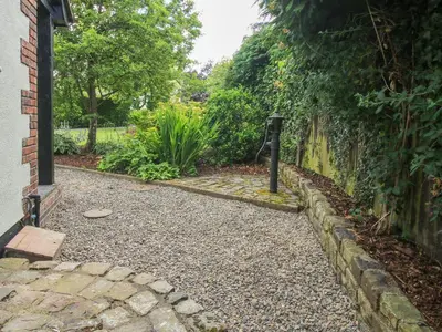 a garden with a stone walkway next to a building at 1 Clarkes Lane in Oswestry
