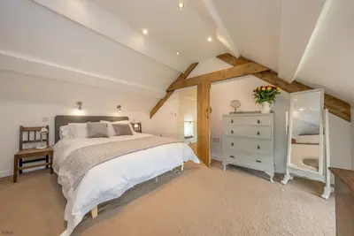 a bedroom with a bed with a dresser and a mirror at Pengwern in Cerrigydrudion