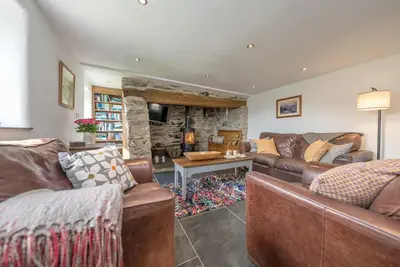 a living room with leather furniture and a stone fireplace at Pengwern in Cerrigydrudion