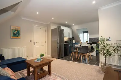 a living room with a blue couch and a kitchen at Professionals welcome - Near Town Centre - Free Parking-Sleeps 4 in Shrewsbury