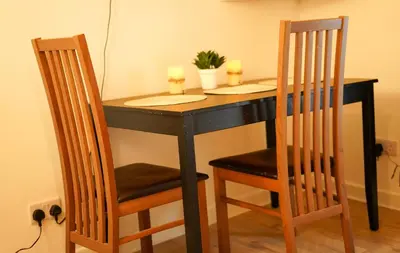 a black table with two chairs and two candles on it at FLAT 2 Seven Cambrian Square First Floor Flat in Newtown