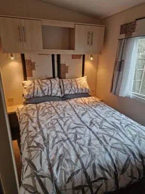 a bedroom with a large bed with a comforter at Premium 3 Bedroom Static Caravan with Sea Views Aber Bay in Aberystwyth