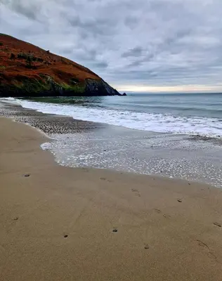 a sandy beach with the ocean and a hill at Premium 3 Bedroom Static Caravan with Sea Views Aber Bay in Aberystwyth